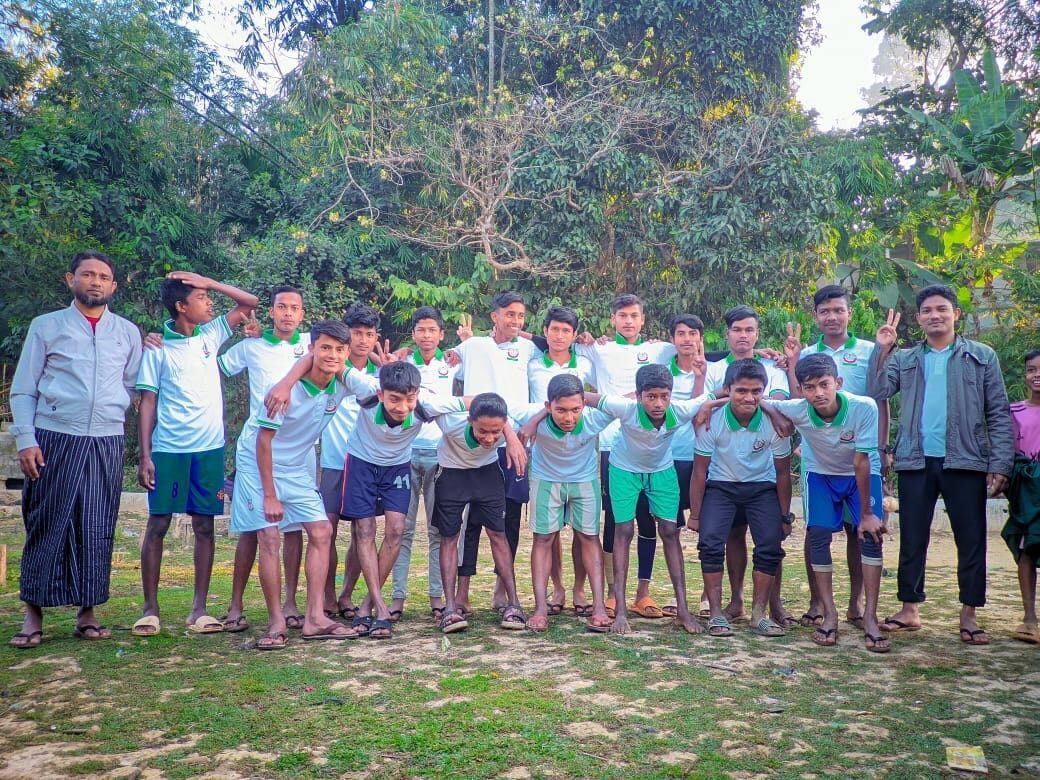 Squad photo of students in green and white school kit standing on grass