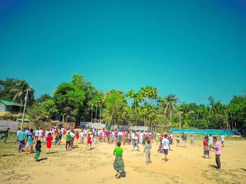 Wide view of the school ground filled with students and spectators under a clear sky