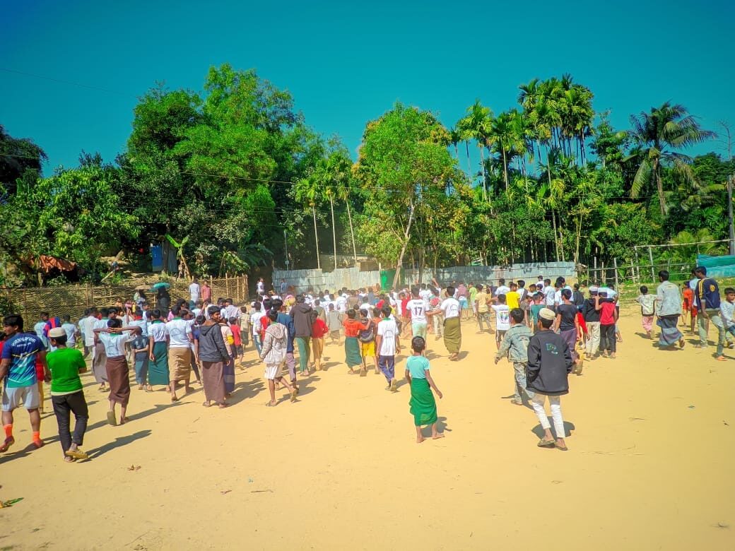 Students and spectators crossing the sandy field between matches