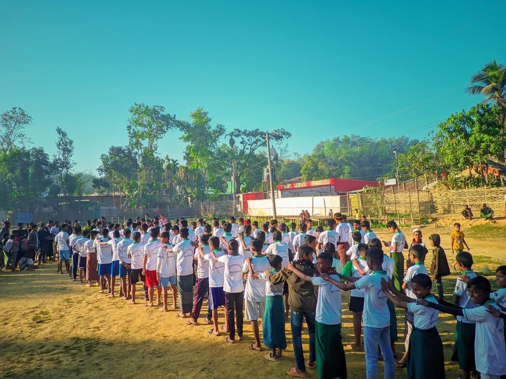 Long lines of students in school shirts assembled across the ground